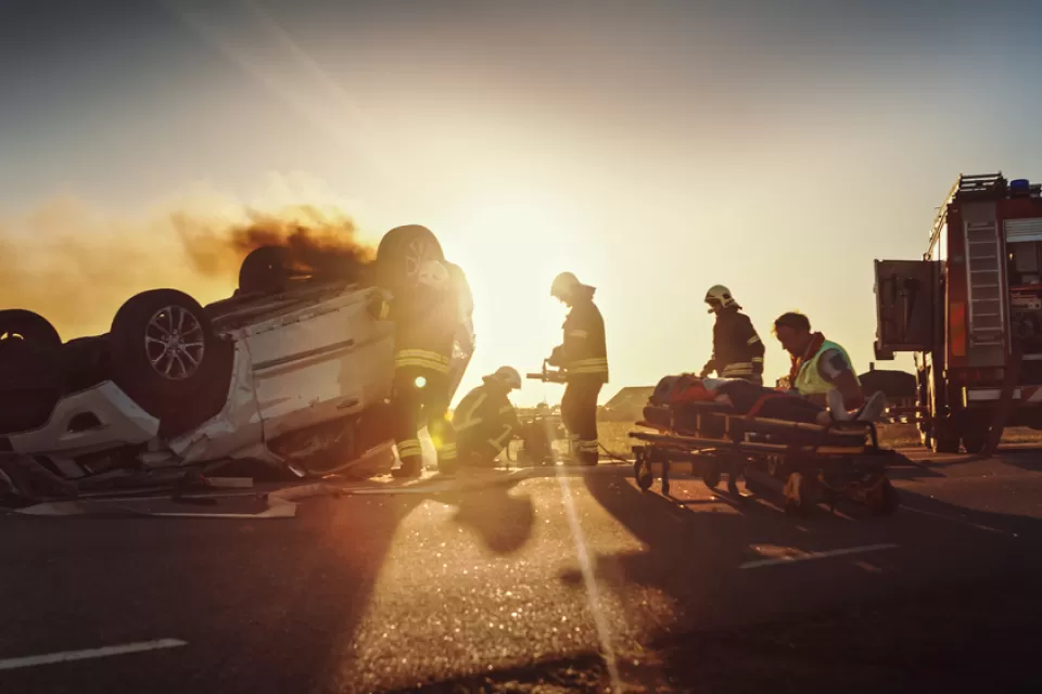 OVerturned vehicle with fire truck and firefighters assisting